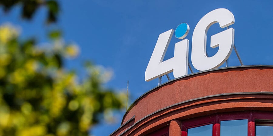 Alt text: 4iG logó a vállalat budapesti székházának tetején, kék ég háttérrel.